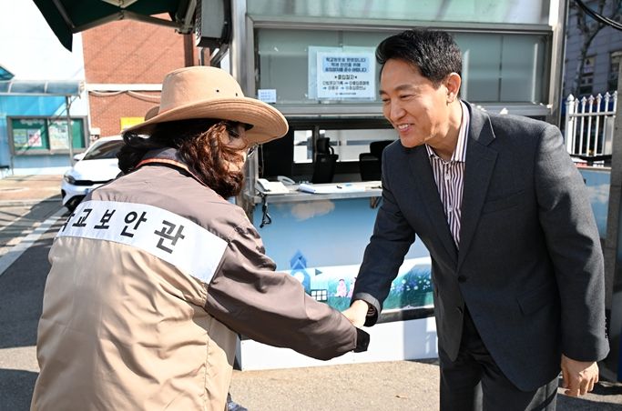 오세훈 서울시장이 13일 서울 소재 초등학교에서 학교보안관과 인사를 나누고 있다.